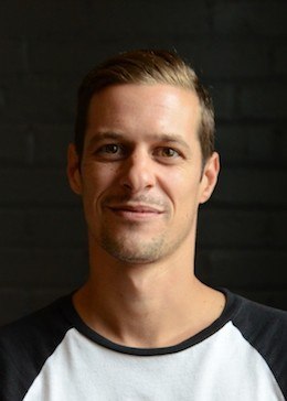 Jean-François in a black and white shirt in front of a black background