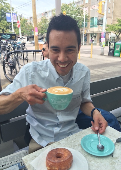 Réjean drinking a latte and eating a doughnut